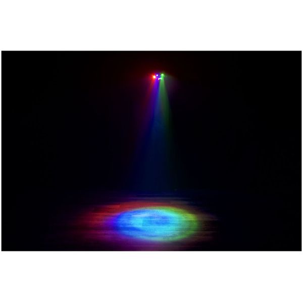Alt-text: “Eliminator Furious Three RG som lyser med röda, gröna och blå spotlights i mörker och skapar en färgad ljuscirkel på golvet.