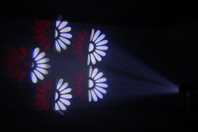Ljuseffekt från Moving Head 3-FX-in-1 – projicerar röda och vita blomformade mönster i rörelse genom rök för en dynamisk scen- eller festbelysning.
