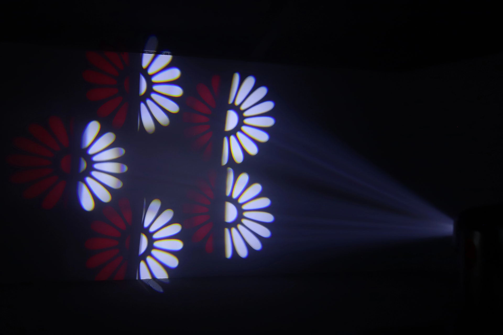 Ljuseffekt från Moving Head 3-FX-in-1 – projicerar röda och vita blomformade mönster i rörelse genom rök för en dynamisk scen- eller festbelysning.