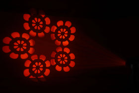 Rött blomformat ljusmönster projicerat av moving head-lampa med flera gobos – en effektfull ljusprojektion för scen och fest.