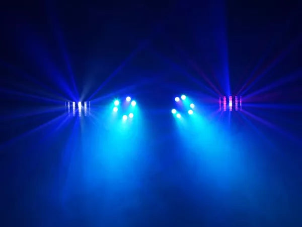 Blå och lila ljusstrålar från partybelysning som skapar dimmig atmosfär på dansgolv.